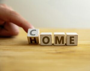 Come home concept. Hand flips letter on wooden cube changing the word home to come.