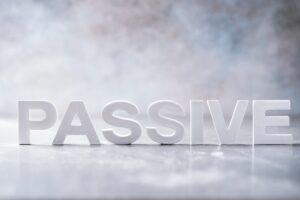 Word PASSIVE made with cement letters on grey marble background. Copy space. Business concept